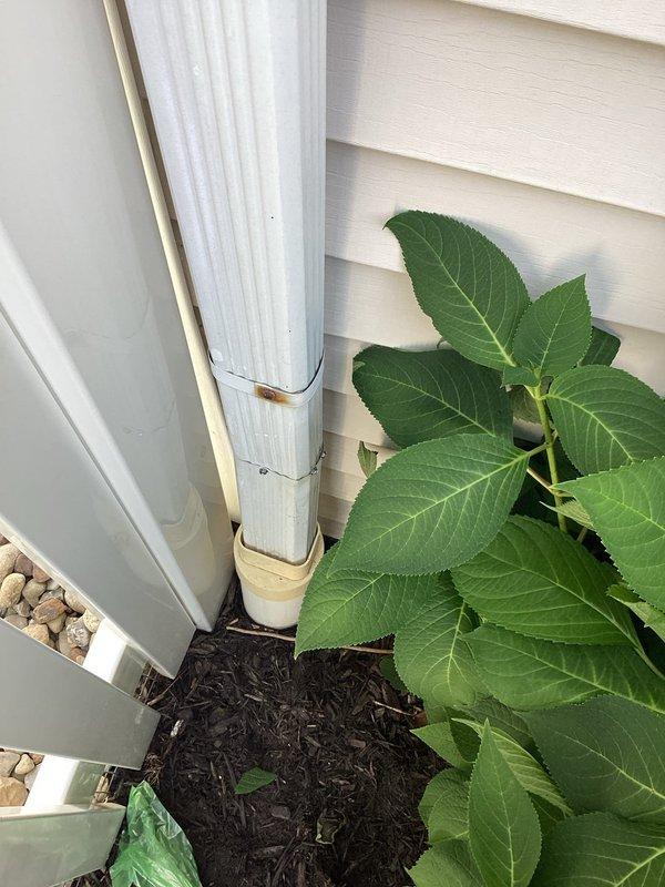 Replaced missing one-foot section of white vertical downspout on right side of building exterior. The downspout system was restored to proper functionality, ensuring effective drainage from the roof to ground level and preventing water damage to the building foundation and landscaping.