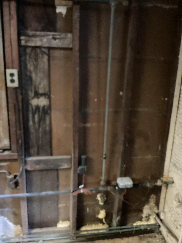 Responded to service call for gas line relocation and plumbing leak repair. Upon arrival, assessed existing gas line configuration and confirmed gas supply was already shut off. Evaluated basement utility area with exposed framing to determine optimal routing for gas line extension to new appliance location. Identified active water leak at sink with visible water damage and staining on adjacent wall surfaces. Initiated drywall removal around affected plumbing area to access leak source and assess extent of water intrusion damage. Documented existing conditions including deteriorated wall materials, exposed piping, and rust staining patterns indicating prolonged moisture exposure. Return visit scheduled to complete drywall cutout, repair water leak at sink connection, and install relocated gas line to specified termination point.