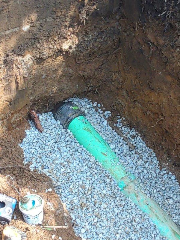 Completed full sewer lateral replacement from house foundation to main line connection. Excavated trench alongside foundation, removed old deteriorated sewer pipe, and installed new green PVC sewer line properly bedded in crushed stone for optimal drainage and support. All excavation work completed with proper depth and grade to ensure gravity flow, pipe secured with appropriate couplings, and system tested for proper function prior to backfill.