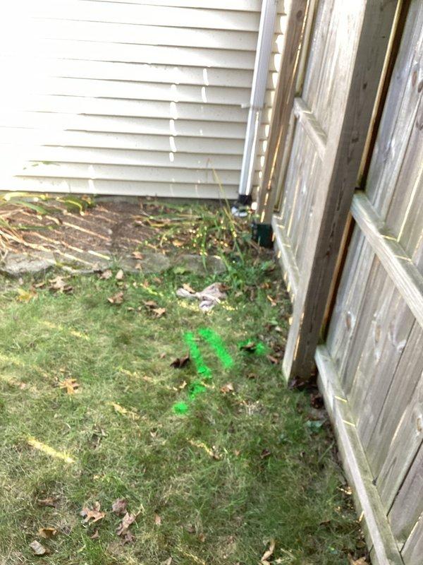 Responded to moisture intrusion issue at exterior wall of lower level split-level home in the downspout area. Upon inspection, identified groundwater drainage problem where downspout discharge was pooling near foundation, causing water penetration through the exterior wall. Marked utility locations and drainage path, assessed the existing downspout configuration and ground grading conditions. Documented site conditions showing inadequate drainage away from foundation and recommended corrective measures to redirect groundwater flow and prevent future moisture infiltration.