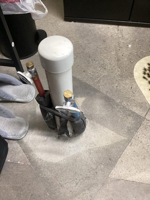 Responded to commercial customer inquiry regarding 2-inch drain and PEX pipe installation protruding through floor. Customer requested assessment and estimate for cutting out 12x12-inch section of flooring and installing floor box to conceal plumbing connections. Documented existing installation with photographs showing copper piping with brass fittings and white cylindrical component with blue flex line connection on gray tile floor. Forwarded inquiry and documentation to management for feasibility review and pricing determination.