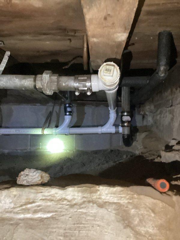 Replaced deteriorated kitchen drain pipe and rerouted drainage system into existing PVC infrastructure in crawl space. Installation included new white PVC piping with proper support brackets mounted to concrete block wall, ensuring code-compliant slope and secure connections to pre-existing drainage system.