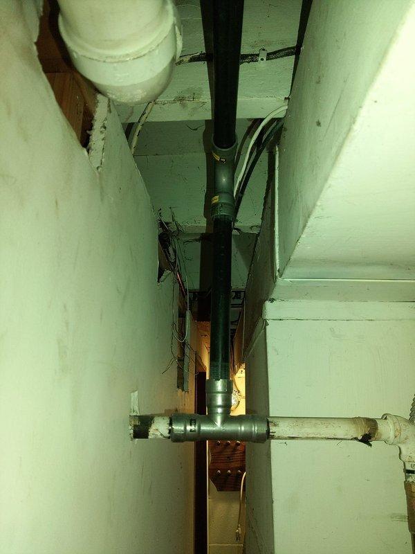 Conducted plumbing estimate for relocation of existing plumbing lines and water heater replacement options. Assessed current tankless water heater installation with associated copper supply piping, PVC venting system, and gas connections in basement utility area. Evaluated confined mechanical space containing vertical black drainage pipe, horizontal supply lines, and existing routing through wooden framing to determine feasibility of relocating plumbing infrastructure and accommodating either a new tankless unit or 75-gallon power vent water heater installation.