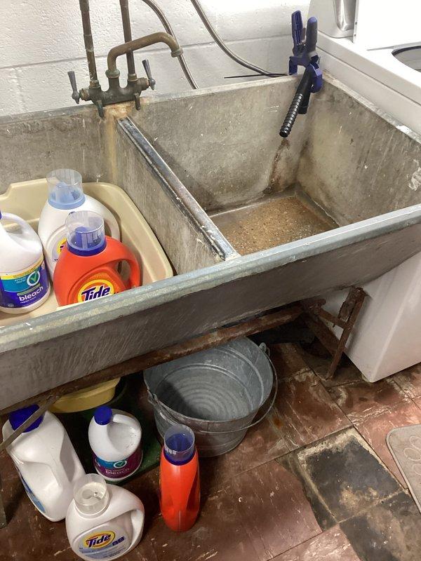 Responded to utility sink repair request where concrete utility tub leg had detached from wall mounting. Upon assessment, evaluated existing plumbing configuration including copper supply lines and drain connections to determine feasibility of converting to double bay sink installation as requested. Examined washer drain routing options to floor drain as temporary solution while permanent fixture replacement is planned. Documented current condition of utility sink area, plumbing connections, and surrounding workspace to provide accurate scope for future installation work.