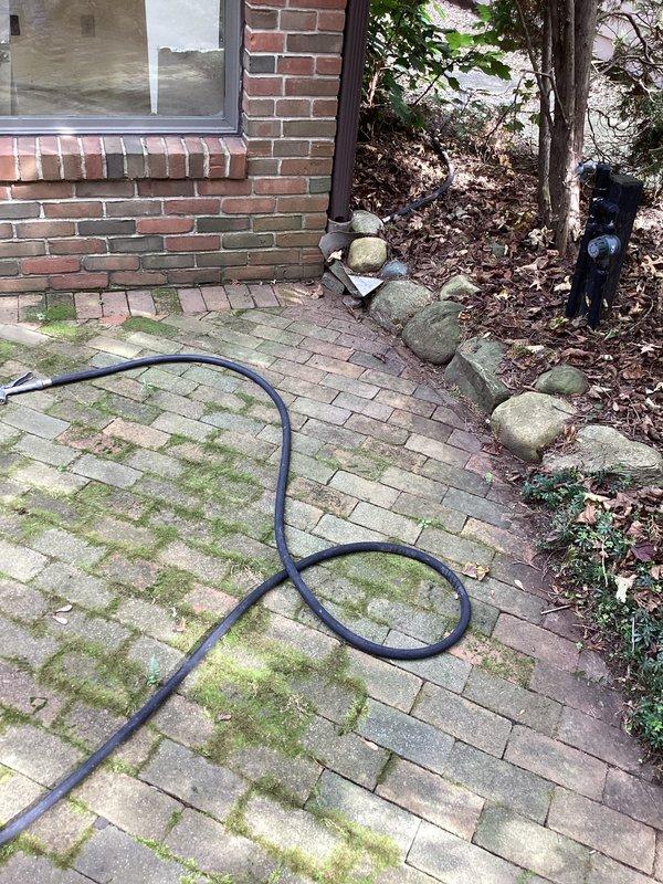 Performed camera inspection of exterior downspout drainage system as requested. Deployed inspection equipment through accessible downspout locations on brick exterior and side yard areas to assess underground drainage line condition and flow path. Documentation captured showing patio area with significant moss growth on pavers and side yard access point with brick paving, confirming proper camera line deployment and completion of requested drainage system evaluation.