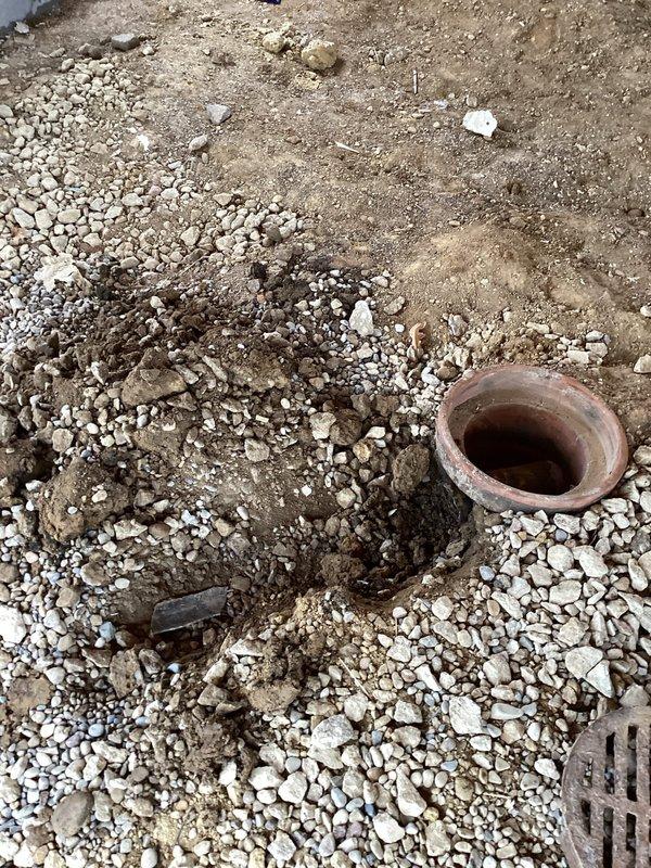 Responded to main drain cleanout service call at residential property that had sustained structural damage from a fallen tree. Upon arrival, located the main cleanout access point near the curb area and performed initial assessment of the drainage system. Excavated soil and gravel around the terracotta clay pipe to expose the cleanout opening for proper access and inspection. 

Cleared debris and examined the main drain line through the exposed cleanout, checking for blockages or damage to the underground drainage system. Assessed the garage floor drain connection as requested to determine if additional repair work would be necessary. Documented site conditions with photographs showing the excavated cleanout area and surrounding property layout for future reference and potential follow-up service needs.