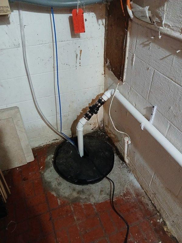 Installed new 1/2 HP sump pump in basement with basin and rerouted discharge line through crawlspace using PVC pipe and fittings. Excavated and installed 4" SDR35 solid PVC pipe for new drainage system, connecting sump pump discharge and three gutter downspouts to existing 4" line near detached garage. All piping secured with proper mounting brackets and fittings, creating complete drainage solution for foundation water management.