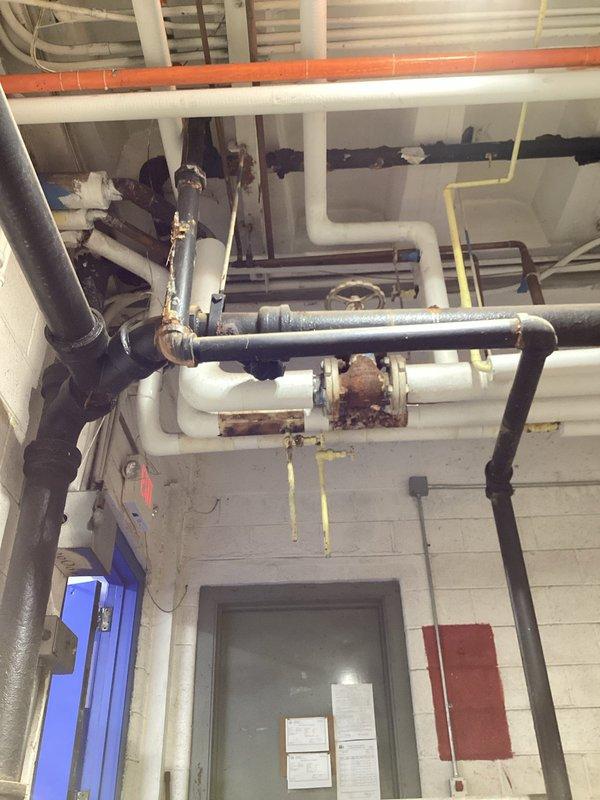 Inspected the drain system serving the floor drain and dishwasher lines and found the cast iron drain piping to be heavily corroded and deteriorated, with rust staining and scaling at fittings, joints, and couplings throughout the overhead and below-grade runs. Based on the extent of the corrosion, an estimated 60 feet of 4-inch cast iron drain line and 40 feet of 1.5-inch cast iron branch piping, including the two branch lines serving the floor drain and dishwasher, require replacement to restore reliable drainage. Documented existing conditions with photos and recommended full replacement of the affected piping.