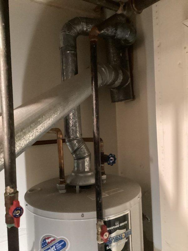 Conducted estimate for furnace replacement (model est9-11a). Visual inspection revealed existing water heater installation with proper ventilation and plumbing connections. Noted copper piping with valves and drainage system components that would need to be coordinated with new furnace installation.