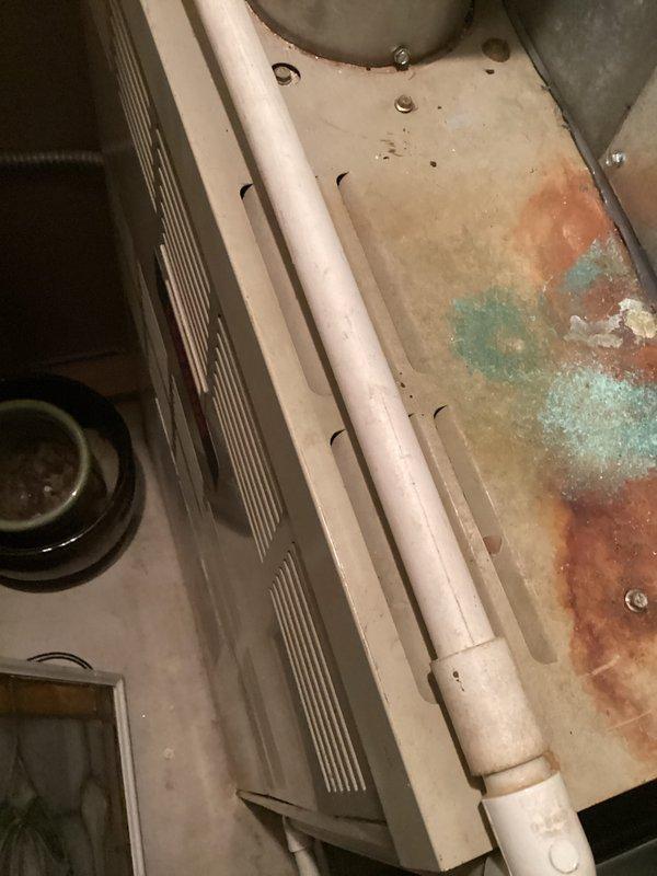 Inspected 33-year-old water heater showing significant deterioration, corrosion, and water leakage. Observed turquoise and rust-colored staining on tank surfaces, indicating advanced deterioration. Recommended complete replacement of the aging unit due to safety concerns and declining efficiency.