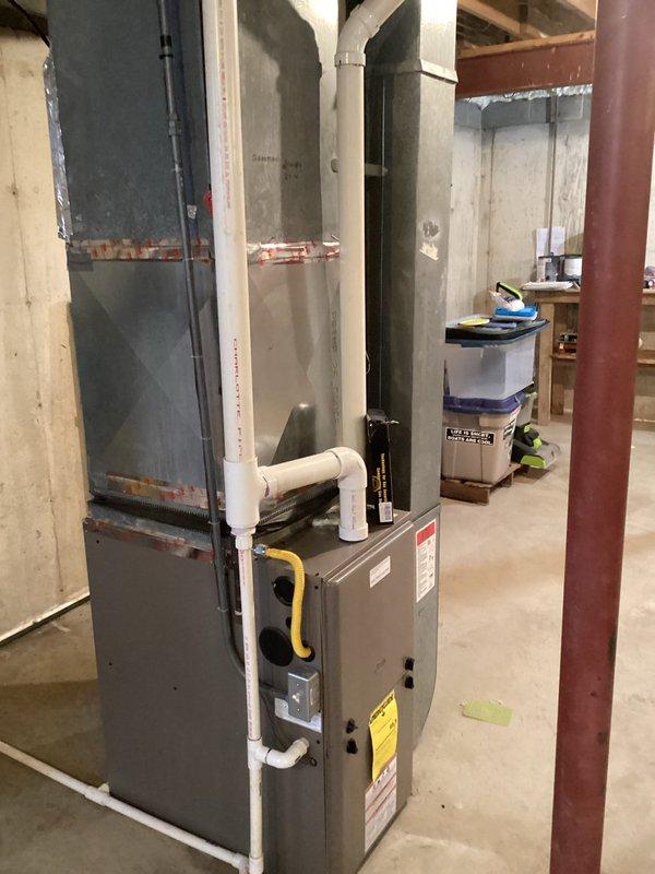 Conducted assessment for furnace replacement quote on 12-year-old unit located in unfinished basement of residential property. Existing system features standard PVC venting and is positioned against concrete wall with nearby ductwork connections. Documented current installation configuration to prepare accurate replacement options for homeowner.
