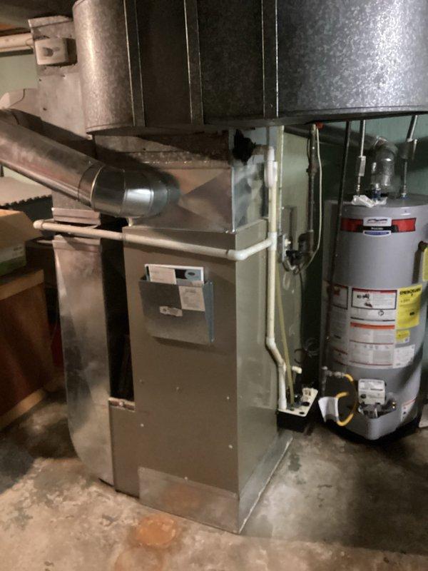 Conducted a replacement estimate for a 16-year-old but functional furnace system located in customer's basement. Visual inspection revealed an aging natural gas furnace with connected ductwork and adjacent water heater. System evaluation included examination of existing ventilation components, insulated ductwork, and associated plumbing connections to determine appropriate replacement options.