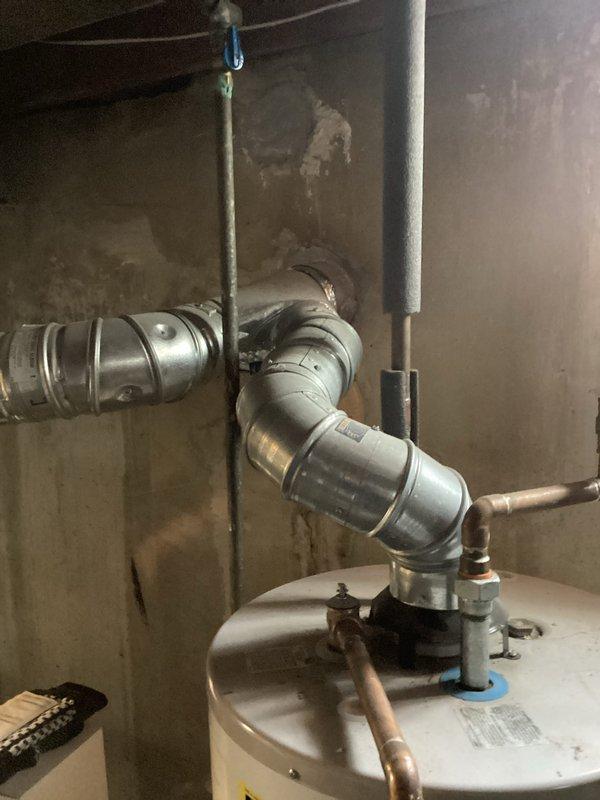 Conducted assessment of 21-year-old gas furnace in basement of 1400 sq ft brick ranch home. Documented existing HVAC system, water heater installation with connected galvanized ductwork, and inspected electrical panel to evaluate power supply capabilities for potential replacement unit. Photos taken of utility area and circuit breaker configuration for proper system sizing and installation planning.