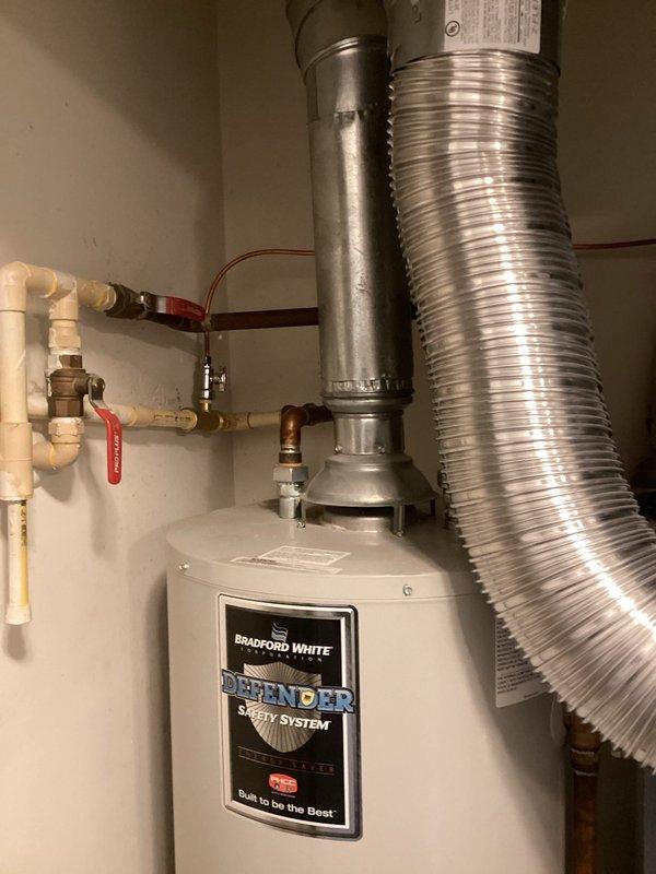 Performed comprehensive inspection of Bradford White "Defender" water heater installation. System appears properly installed with appropriate ventilation via metal flue pipe, functional PVC and copper water connections, and operational shutoff valve. Water heater shows normal working condition with no visible damage or deterioration. All safety components intact and warning labels properly displayed.