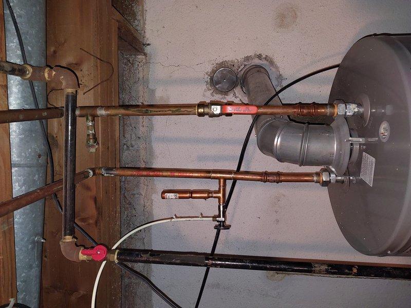 Conducted scheduled furnace maintenance under Worry Free Service Agreement. Inspected water heater system and associated copper piping, noting some wall staining near connections that may indicate minor leakage. Observed functional but aging installation with proper venting and valve operation.