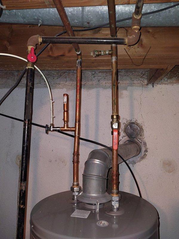 Conducted scheduled furnace maintenance under Worry Free Service Agreement. Inspected water heater system and associated copper piping, noting some wall staining near connections that may indicate minor leakage. Observed functional but aging installation with proper venting and valve operation.
