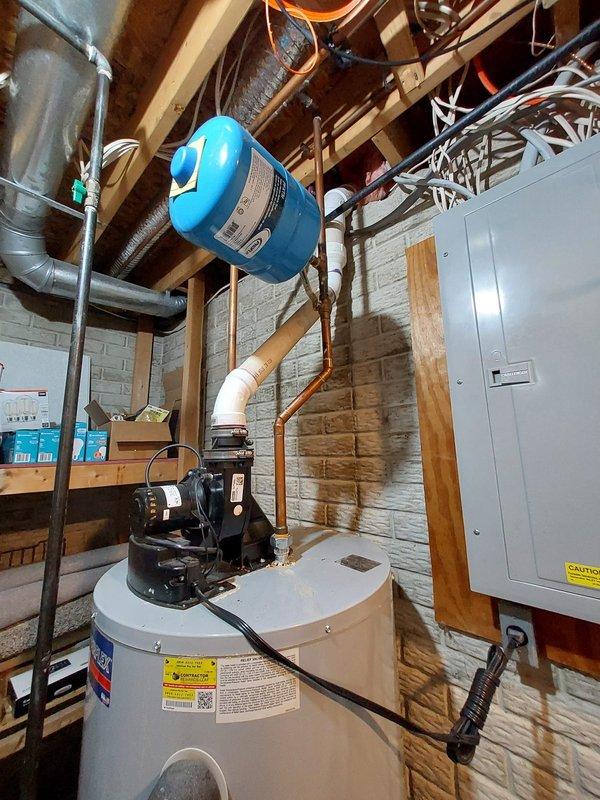 Responded to service call for water heater leaking from top connection. Inspected residential utility room with existing tank water heater system and blue expansion tank. Repaired top connection leak, tested system for proper operation, and documented with photos of the installation area.