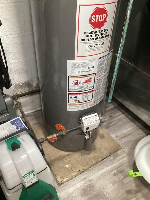 Conducted tankless water heater assessment (EST 12-2) in residential utility area, documenting current installation which includes a conventional tank-style unit with copper piping and gas valve connections. Inspection revealed existing plumbing infrastructure with PEX water lines and PVC drain pipes running through ceiling joists, providing necessary information for potential tankless conversion.