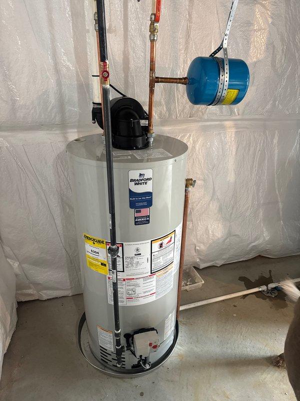 Successfully installed a 50-gallon Bradford White water heater with all necessary connections and safety components. Installation included proper fitting of copper supply lines, shutoff valves, and a blue expansion tank mounted on metal brackets. All connections were tested and verified to be leak-free with system functioning as designed.