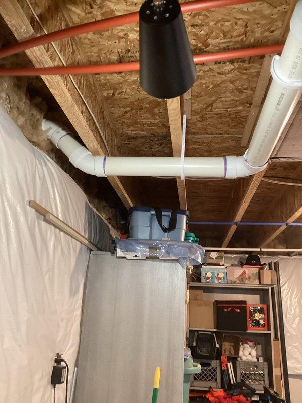 Conducted water heater estimation in unfinished basement utility area featuring exposed ceiling joists with extensive plumbing infrastructure including red/blue supply lines and PVC drainage pipes. Assessment included evaluation of current installation conditions, space requirements, and necessary connections for proper replacement, with photo documentation taken of the mechanical room setup for accurate quote preparation.