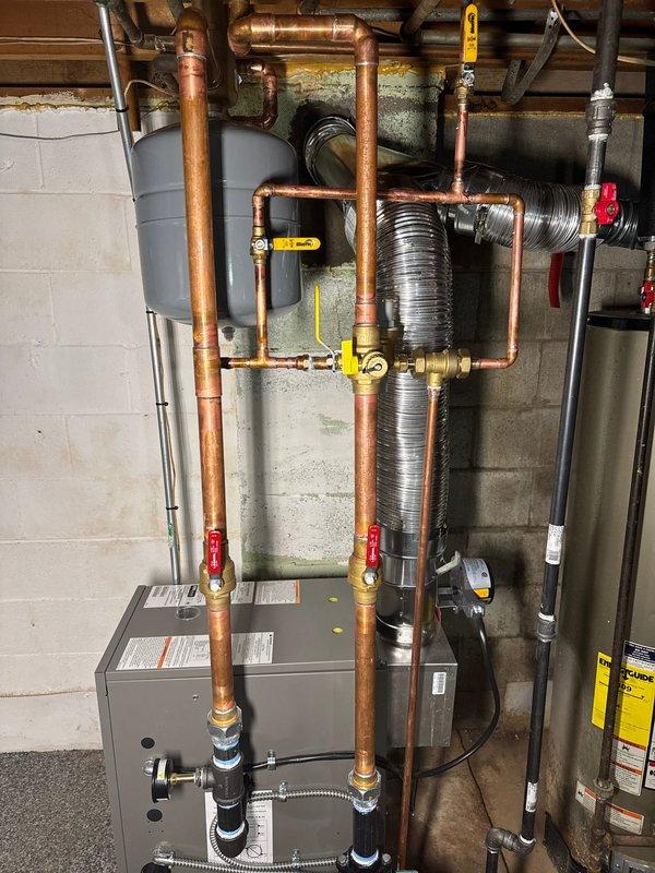 Successfully installed a new Lennox boiler system with T6 Thermostat and chimney liner according to sales specifications. Installation included proper configuration of copper pipe network with multiple shut-off valves, pressure gauge mounting, and connection to expansion tank. System was fully tested with all components functioning as designed.