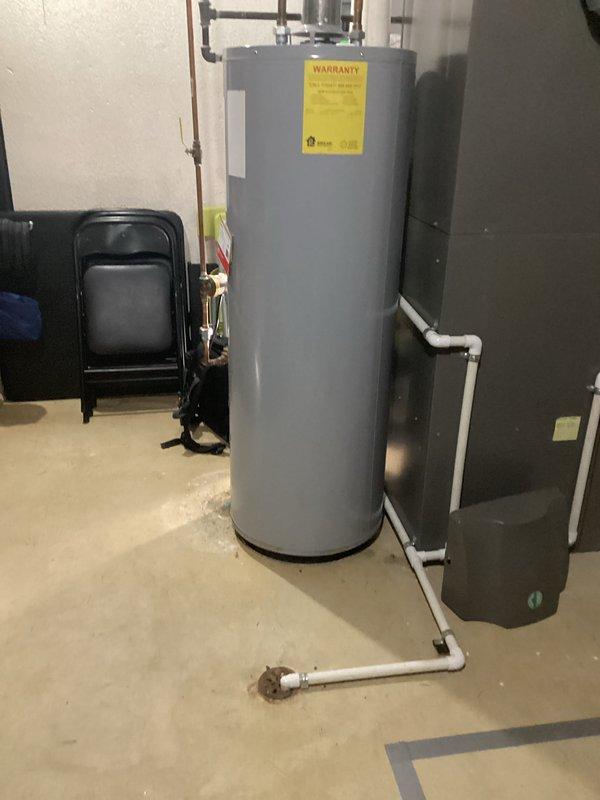 Conducted site assessment for water heater replacement quote. Documented existing system consisting of a cylindrical tank with copper supply lines and PVC drainage piping in utility room with adjacent HVAC equipment. Photographed installation area to develop accurate replacement specifications.