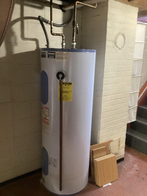 Conducted assessment of heat pump water heater installation requirements between 3-4pm. Evaluated existing electrical infrastructure, including older fuse box and circuit breaker panel, to determine compatibility with new heat pump unit. Photographed current cylindrical water heater with copper pipe connections and documented electrical configuration for proper replacement specifications.