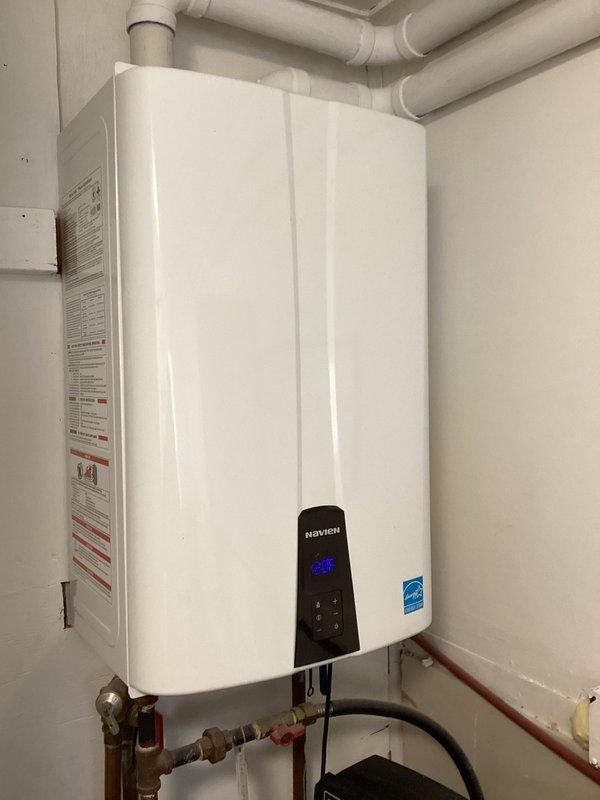 Performed evaluation of Navien tankless water heater system (displaying 80°F on control panel) and assessed associated plumbing components including copper supply lines, PVC venting, pressure regulator, and main shutoff valve with brass fittings. Documented current installation configuration for estimate purposes, noting all components appear to be in good working condition with proper installation of exhaust/intake system.