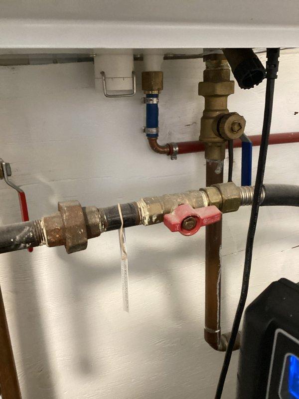 Performed evaluation of Navien tankless water heater system (displaying 80°F on control panel) and assessed associated plumbing components including copper supply lines, PVC venting, pressure regulator, and main shutoff valve with brass fittings. Documented current installation configuration for estimate purposes, noting all components appear to be in good working condition with proper installation of exhaust/intake system.