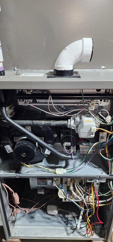 Performed routine maintenance on a forced air furnace system in basement utility area. Inspected all internal components including blower motor assembly, electrical connections, PVC venting, and control boards, confirming proper operation. System appears to be in good working condition with no issues identified during the Worry Free Service Agreement maintenance visit.