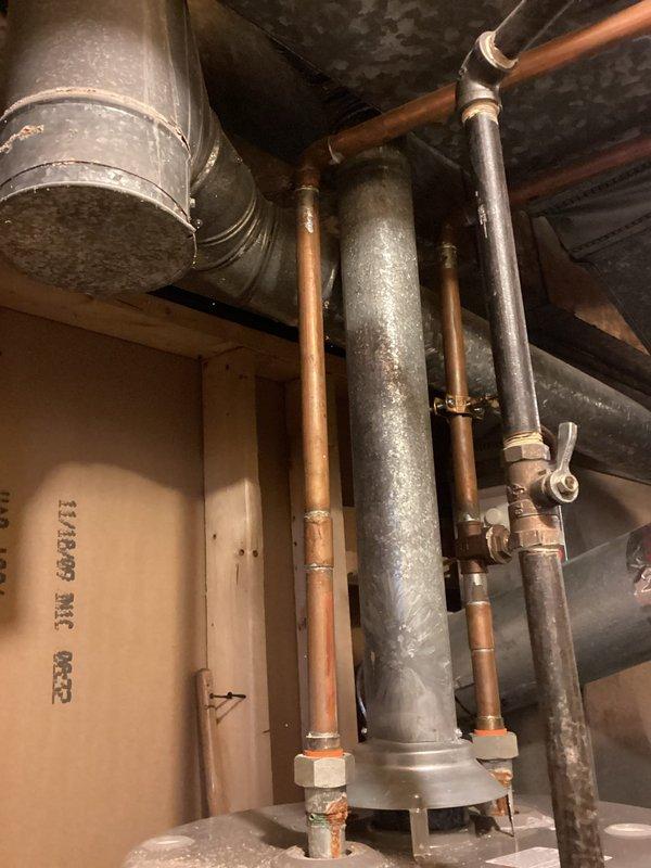Conducted inspection of existing water heater system in utility room for replacement estimate. Examined copper supply lines, ventilation ducting, and shut-off valve functionality. Documented current installation configuration, noting aging components and potential upgrade requirements for proper ventilation and code compliance.