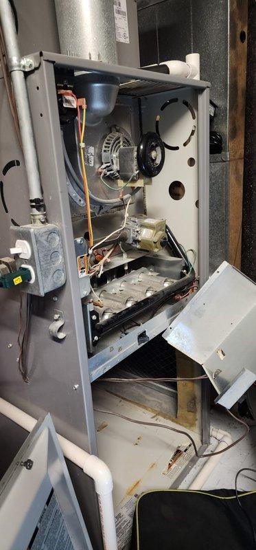 Performed maintenance on Furnace Replacement Number (FRN) system. Opened access panel to inspect interior components including motor, fan assembly, heat exchanger, electrical connections, and control system. Documented overall system condition including ductwork and venting, noting minor surface rust on lower cabinet section.