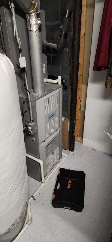 Performed maintenance on Furnace Replacement Number (FRN) system. Opened access panel to inspect interior components including motor, fan assembly, heat exchanger, electrical connections, and control system. Documented overall system condition including ductwork and venting, noting minor surface rust on lower cabinet section.