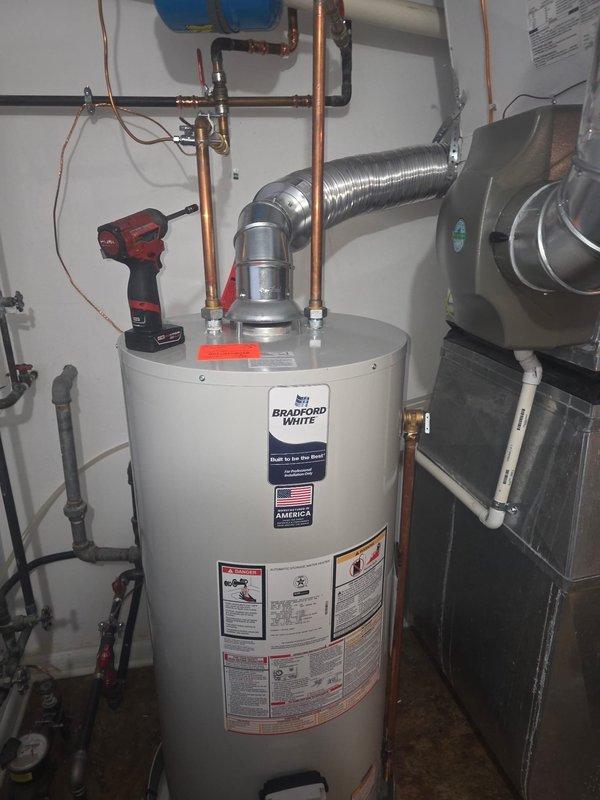 Responded to callback for failed inspection due to negative pitch on water heater vent. Used level to verify improper slope of metal ductwork/ventilation piping. Corrected the installation angle of the Bradford White water heater's flexible metallic vent pipe to ensure proper exhaust flow, bringing the system into compliance with code requirements.