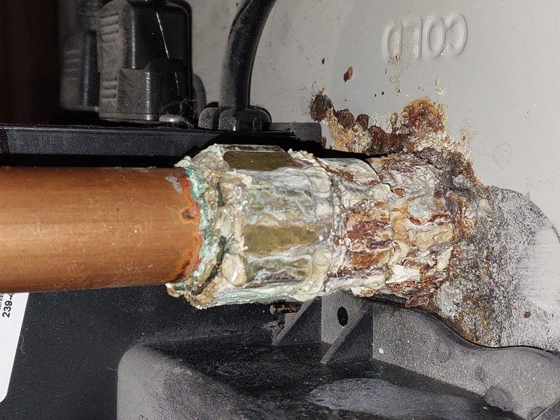 Performed scheduled Worry Free Service Agreement maintenance on heating system during 3-5PM appointment window. Documented significant copper pipe connection deterioration showing advanced corrosion with mineral deposits and rust accumulation. Inspected mechanical unit with circular fan component and adjacent water heater/tank, noting all connections and operational status.