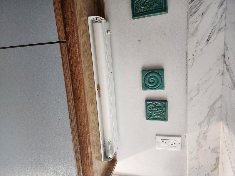 Successfully installed two light fixtures - a fluorescent wall-mounted unit in bathroom/kitchen area near decorative tile work and GFCI outlet, and a rectangular LED fixture on textured wall in hallway/corner location. Additionally installed Ring camera system as requested, ensuring proper mounting and functionality.