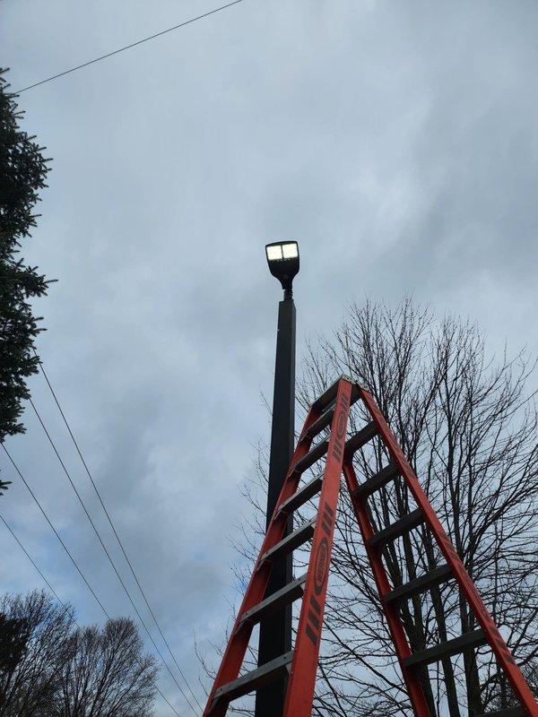 Completed warranty replacement of subdivision lighting fixtures. Utilized extension ladder to access elevated pole-mounted fixtures. Successfully restored outdoor illumination to specified area per warranty requirements.