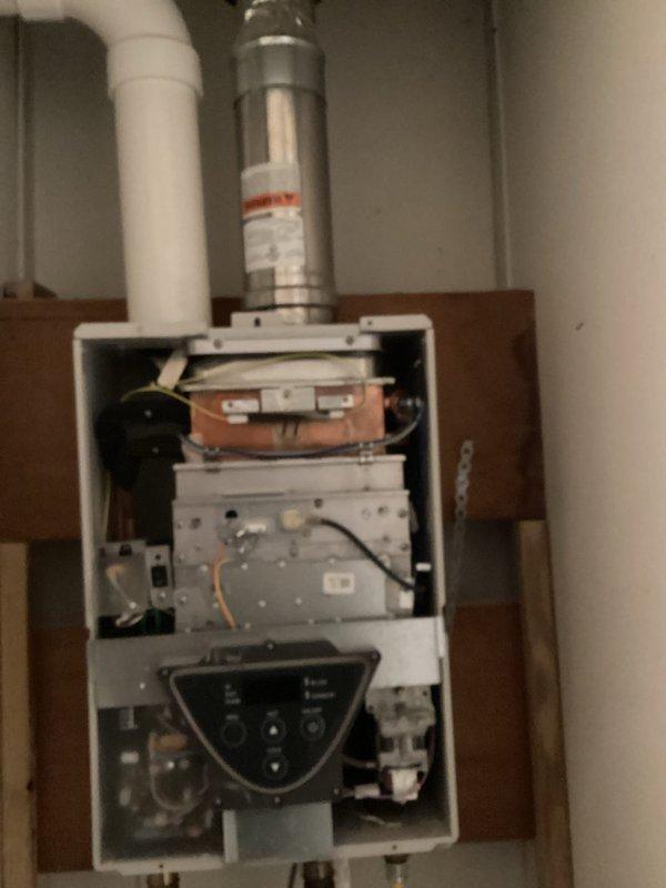 Conducted comprehensive inspection of existing tankless water heater system, documenting deteriorated exhaust venting and aging control panel components. Evaluation revealed need for replacement due to inefficient operation and potential safety concerns with the current installation. Photos taken of internal components and ventilation configuration to support replacement recommendation.