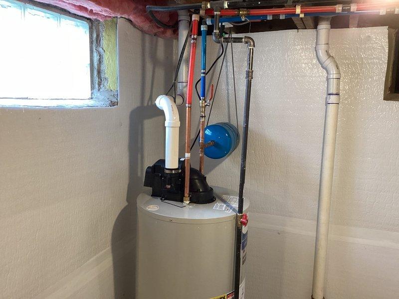 Successfully installed a 50-gallon water heater in utility room, complete with proper copper piping connections for hot and cold water lines. Installed blue expansion tank on adjacent wall and ensured all connections were secure with no leaks, including the white PVC vent pipe and necessary valves.