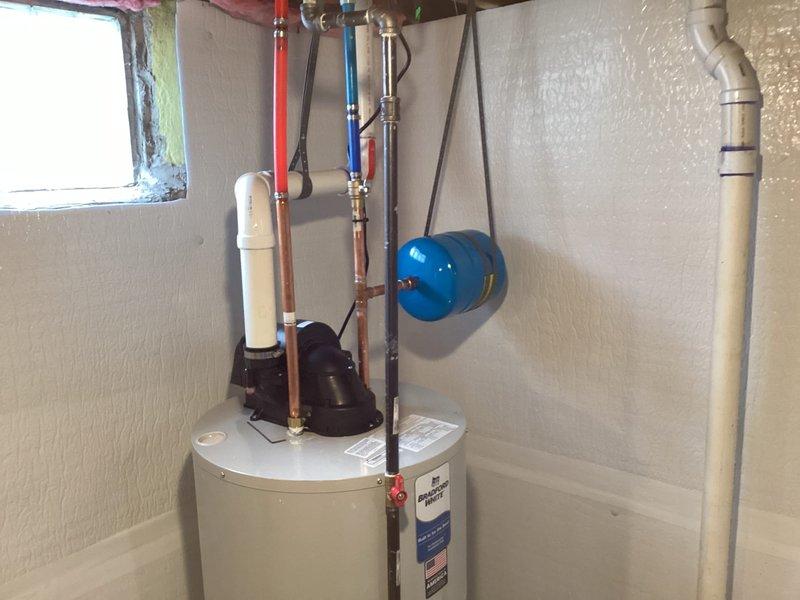Successfully installed a 50-gallon water heater in utility room, complete with proper copper piping connections for hot and cold water lines. Installed blue expansion tank on adjacent wall and ensured all connections were secure with no leaks, including the white PVC vent pipe and necessary valves.