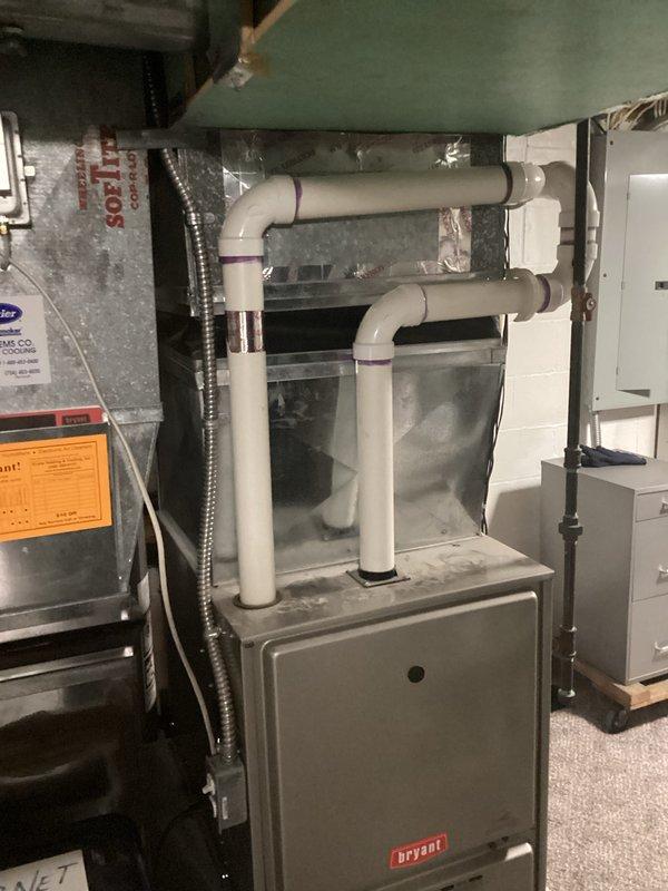 Performed inspection of 35-year-old outdoor air conditioning system on east side of residence. Documented existing Bryant furnace system with PVC venting configuration and associated ductwork in utility area. Also photographed Rheem Performance water heater with copper piping and metal ventilation. Provided replacement estimate for complete AC system upgrade.
