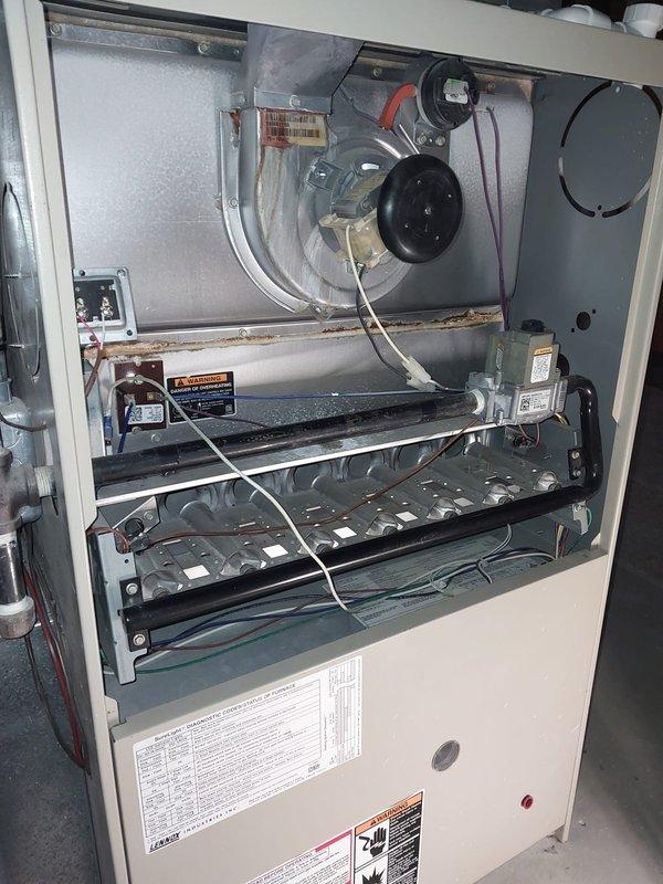 Performed scheduled maintenance on 10+ year old furnace. Inspection revealed significant rust and water accumulation in the heat exchanger compartment, indicating possible condensation issues or drainage problems. System was cleaned, components tested, and customer advised about corrosion concerns that may require replacement in near future due to age-related deterioration.