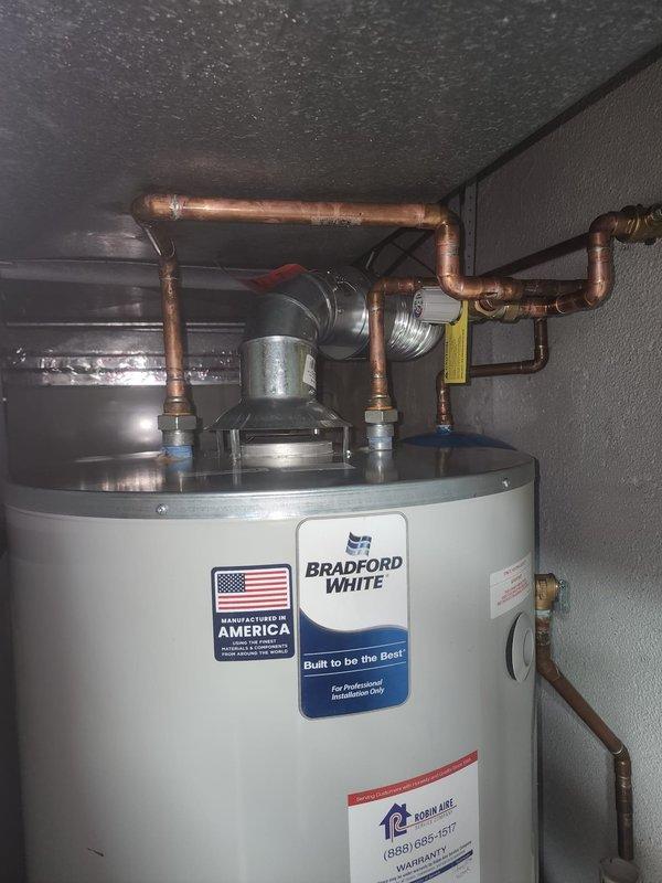 Replaced mixing valve on Bradford White water heater system. Performed temperature testing at sink fixtures to confirm proper operation, with readings showing 22.3°C. Installation includes appropriate copper pipe connections, valves, and proper venting.