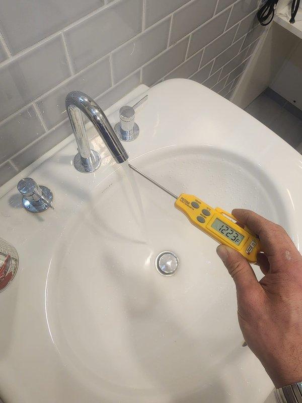 Replaced mixing valve on Bradford White water heater system. Performed temperature testing at sink fixtures to confirm proper operation, with readings showing 22.3°C. Installation includes appropriate copper pipe connections, valves, and proper venting.