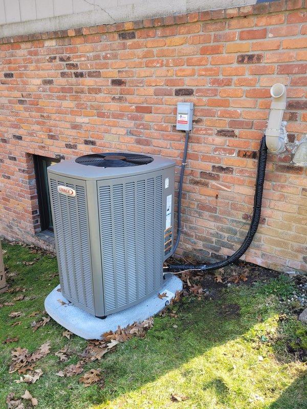 # HVAC Complete System Installation

Successfully completed full HVAC system replacement including installation of new Lennox furnace, Lennox air conditioning condenser unit, S40 smart thermostat, and whole-home humidifier. Removed existing equipment and replaced refrigerant lineset to ensure optimal system performance and efficiency. 

New outdoor condenser unit positioned on concrete pad against building exterior with proper clearances maintained for airflow and serviceability. Electrical disconnect box mounted on exterior wall with appropriate conduit routing. All refrigerant lines, electrical connections, and condensate drainage properly installed per manufacturer specifications and local codes.

Indoor furnace installation completed with integration of humidifier for enhanced comfort control. S40 thermostat installed and programmed, providing advanced climate control features and system monitoring capabilities. All components tested and verified operational. System charged to prop