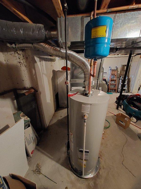 Successfully installed a new 50-gallon residential tanked water heater in the basement mechanical room. The installation included proper connection of hot and cold water supply lines using copper piping, installation and mounting of a blue expansion tank suspended from ceiling joists to protect against thermal expansion, and integration with existing plumbing infrastructure. All connections were secured according to manufacturer specifications and local plumbing codes, with the unit properly positioned on the concrete floor for optimal access and maintenance. The installation ensures reliable domestic hot water supply for the residence.