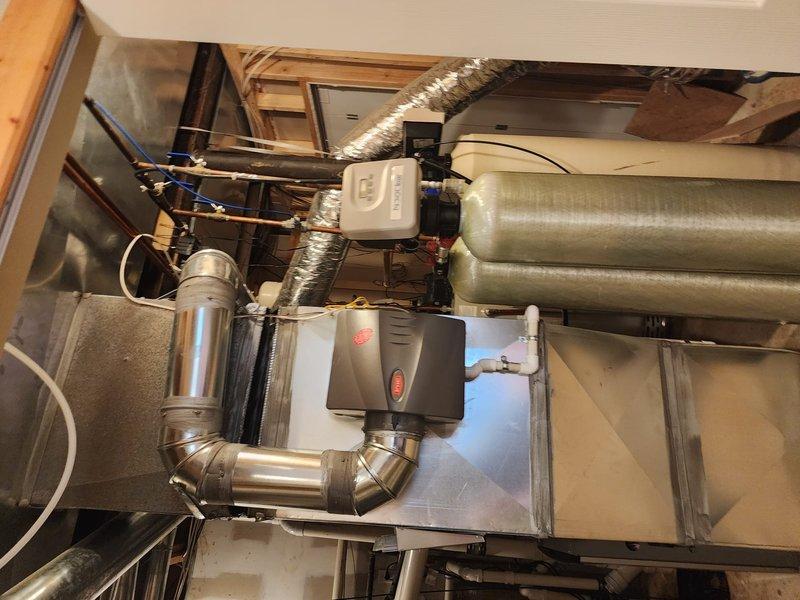 Responded to callback for failed inspection correction related to compressed canvas connector on return duct system. Inspected and photographed attic installation showing flexible ductwork routing, documented existing condition of canvas connector requiring correction per inspection notes. Evaluated basement airflow distribution through registers and confirmed temperature differential of approximately 10 degrees between basement and upper living areas, consistent with previous system performance indicating potential airflow restriction or inadequate duct sizing to lower level zones.