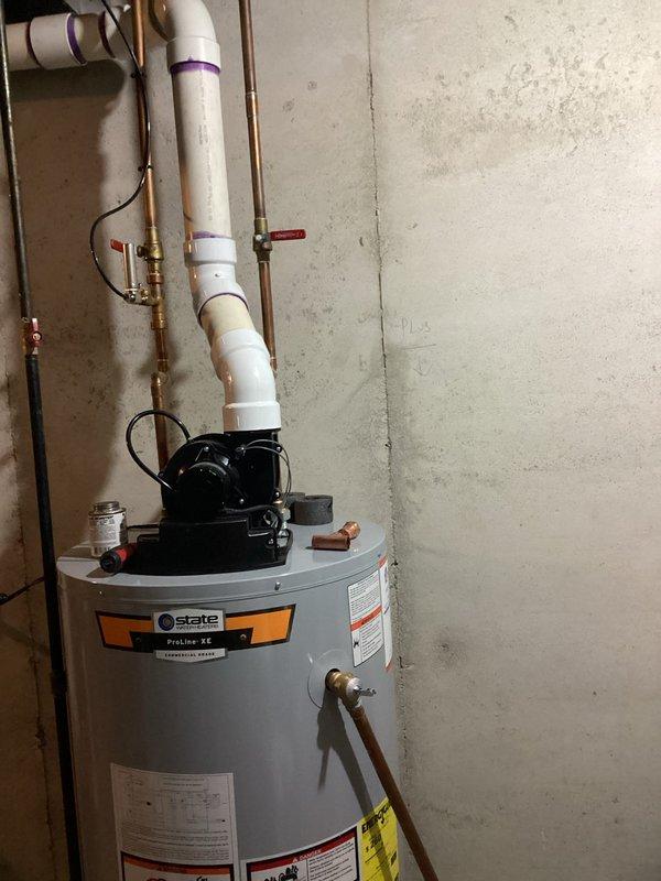 Responded to service call for intermittent dripping from discharge valve on residential water heater in basement of 32-year-old home. Upon inspection, identified temperature and pressure relief (TPR) valve discharge pipe experiencing periodic leakage over four-day period. Evaluated water heater system including circulator pump assembly, copper and PVC supply lines, shut-off valves, and venting configuration. Tested TPR valve operation and inspected for mineral buildup, sediment accumulation, and excessive pressure conditions that could cause intermittent discharge. Examined tank condition, verified proper temperature settings, and assessed overall system integrity. Checked expansion tank pressure and functionality to ensure proper thermal expansion management. Documented existing installation with photographic evidence showing gray cylindrical tank water heater with mounted circulation pump, brass fittings, red-handled shut-off valves, and proper pipe transitions from PVC to copper. Ad