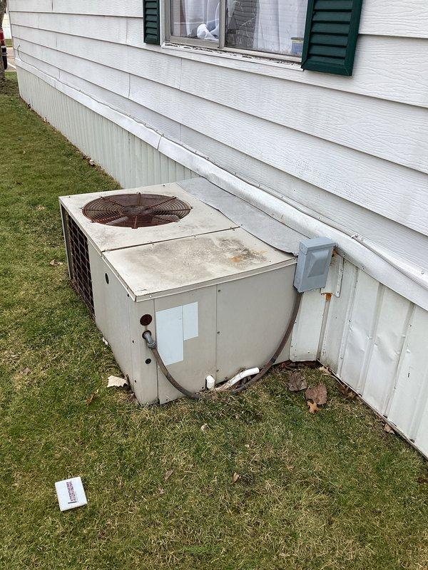 Completed on-site evaluation for HVAC system replacement estimate. Documented existing outdoor condensing unit showing significant age-related deterioration and weathering, currently installed without proper concrete pad placement. Assessed indoor air handler with grille-style return air access point. Photographed equipment conditions and installation configurations to support comprehensive replacement proposal for complete system upgrade.