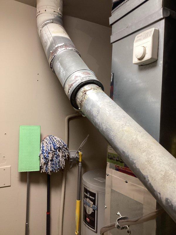 Completed comprehensive HVAC system assessment for furnace replacement estimate at residential property. Documented existing Carrier furnace unit, associated ductwork, venting systems including PVC condensate drainage, and metal flue pipe configuration. Photographed current equipment condition showing age-related wear, discoloration on ductwork and flue components, and overall mechanical room layout to provide accurate replacement specifications and scope of work for property management approval.